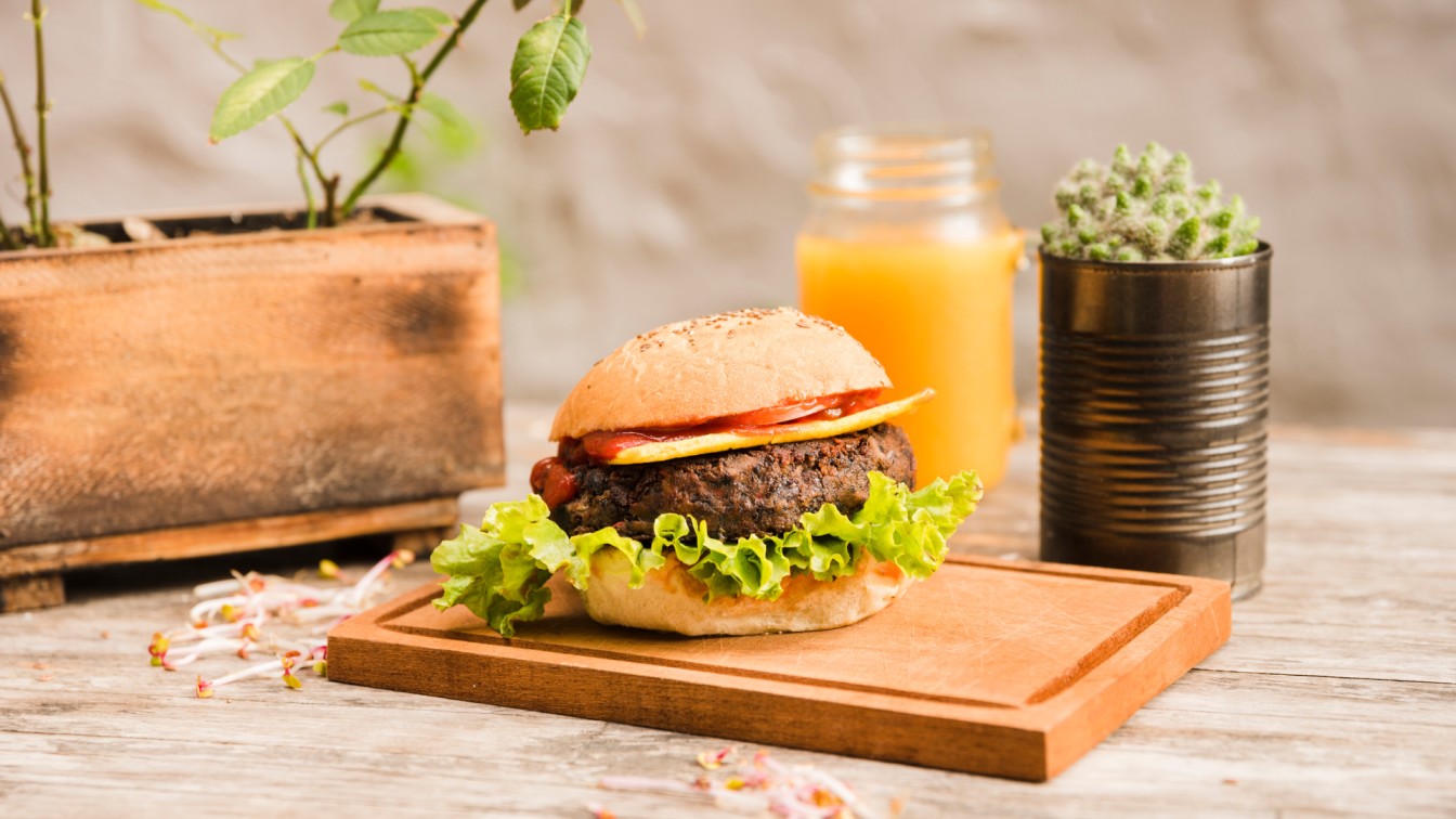 A-delicious-hamburger-with-tomato-lettuce-and-cheese-displayed-on-a-wooden-cutting-board-labeled-as-Best-CBR-Burger-under-10