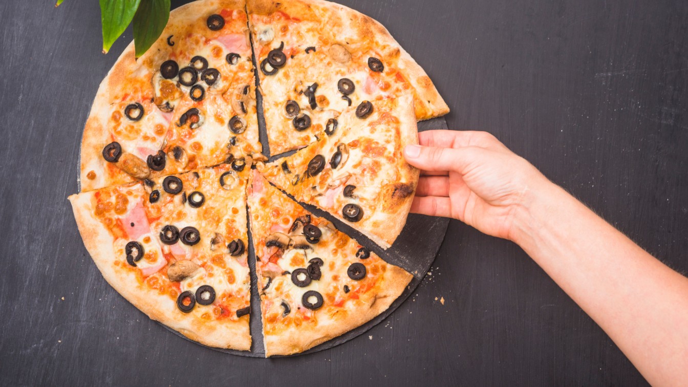 A-person-holds-a-pizza-topped-with-olives-showcasing-a-delicious-option-for-finding-your-perfect-pizza-slice